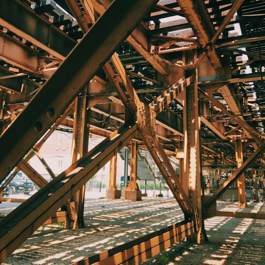 Rusty steel beams form an intricate pattern under a bridge in Chicago.